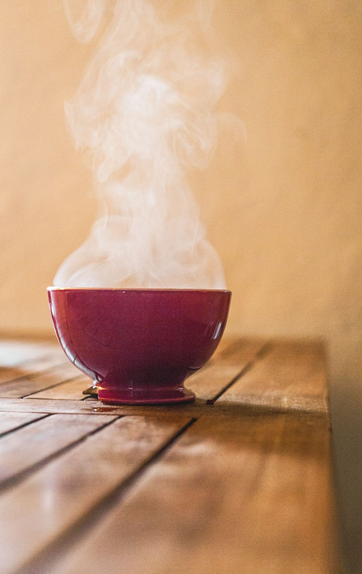 A steaming bowl of soup on a wooden table.